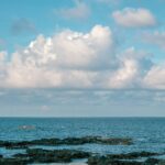 Peaceful coastal scene featuring rocks and sea under a bright blue sky in Bình Thuận, Vietnam.
